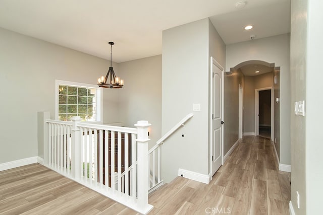 corridor with a chandelier and light hardwood / wood-style floors