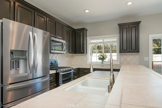 kitchen featuring tile counters, dark brown cabinets, stainless steel appliances, and tasteful backsplash