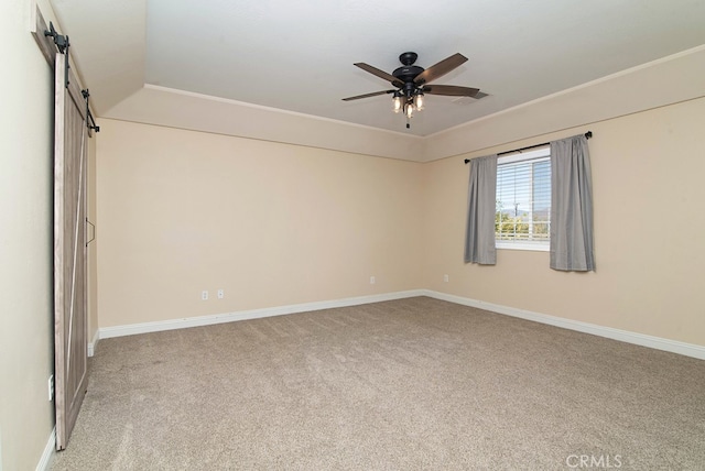 carpeted spare room featuring a barn door, lofted ceiling, and ceiling fan