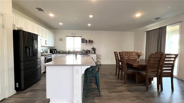 kitchen featuring white cabinetry, a center island, stainless steel range, and black refrigerator with ice dispenser