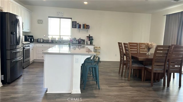 kitchen featuring stainless steel range with gas cooktop, white cabinetry, dark hardwood / wood-style flooring, a center island, and black fridge