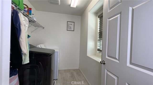 laundry room with washer and clothes dryer and light wood-type flooring