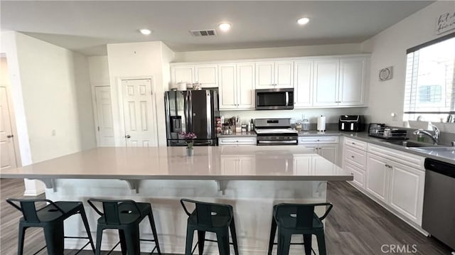 kitchen featuring stainless steel appliances, a center island, sink, and white cabinets