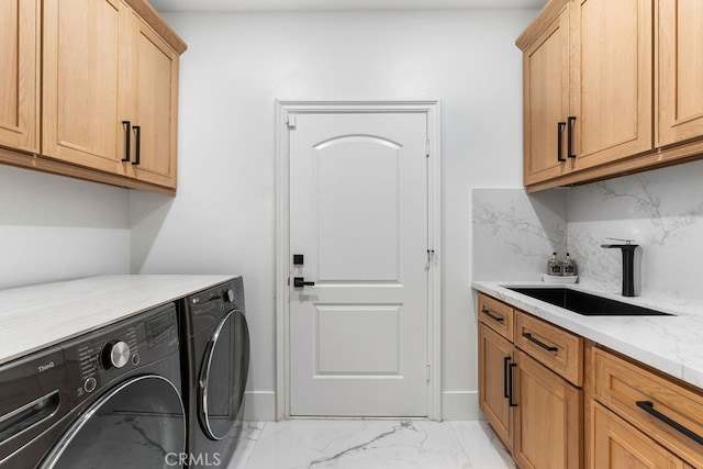 clothes washing area with sink, independent washer and dryer, and cabinets