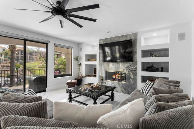 living room featuring ceiling fan, a fireplace, and built in features