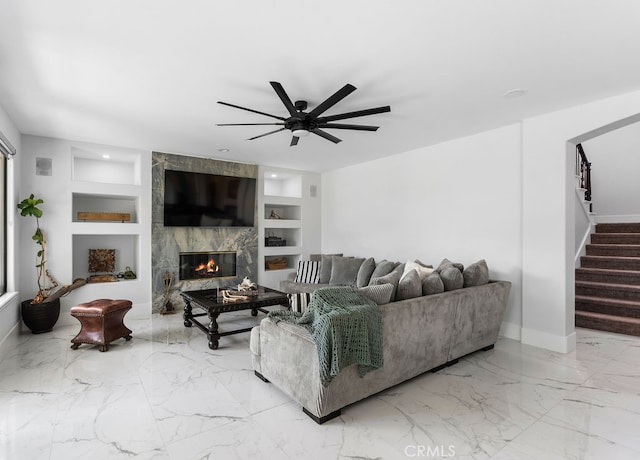 living room with built in shelves, a large fireplace, and ceiling fan