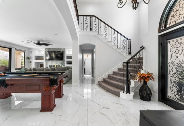 entryway featuring a towering ceiling, a large fireplace, and ceiling fan