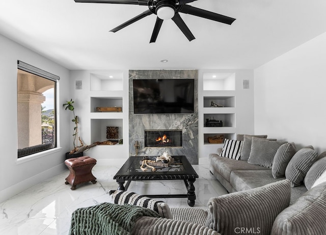 living room with ceiling fan, built in features, and a premium fireplace