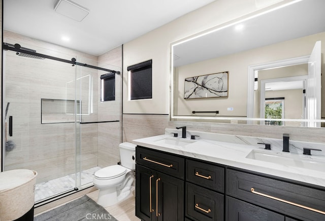 bathroom with tile walls, walk in shower, vanity, and toilet