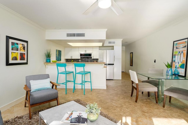 kitchen featuring white cabinetry, kitchen peninsula, white fridge, a kitchen bar, and ornamental molding