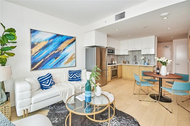 living room with light hardwood / wood-style floors and sink