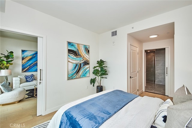 bedroom with ensuite bath and hardwood / wood-style floors