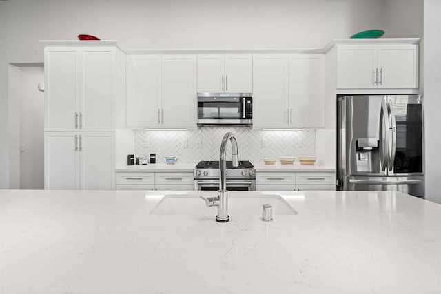 2013 Bravo Loop Unit 5, Chula Vista, CA 91915 - kitchen featuring appliances with stainless steel finishes, tasteful backsplash, white cabinetry, and light stone counters