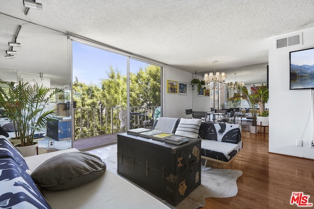 living room with a textured ceiling, a healthy amount of sunlight, hardwood / wood-style floors, and a chandelier