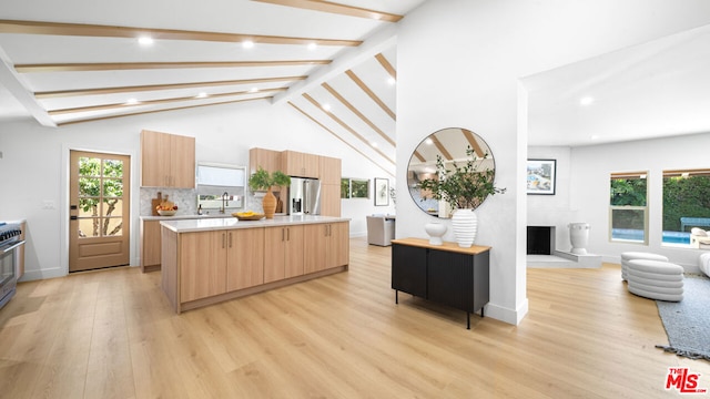 kitchen featuring sink, a center island, stainless steel fridge with ice dispenser, light hardwood / wood-style floors, and backsplash