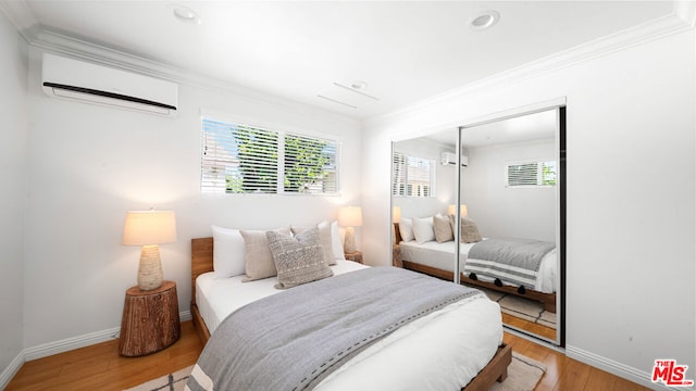 bedroom with multiple windows, light hardwood / wood-style flooring, a wall unit AC, and a closet