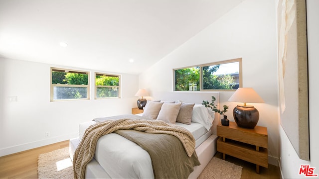 bedroom with multiple windows, vaulted ceiling, and light hardwood / wood-style flooring