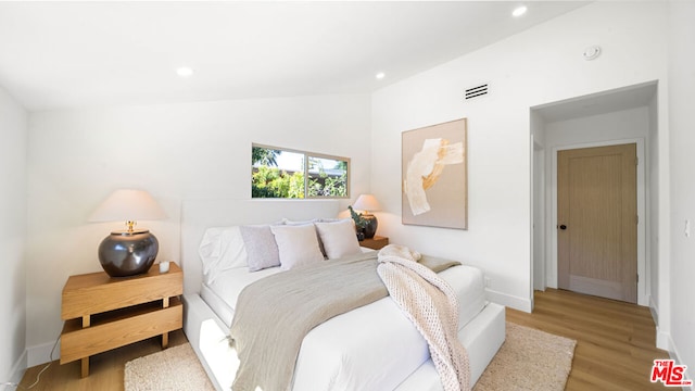 bedroom featuring lofted ceiling and light hardwood / wood-style flooring