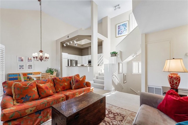 living room with carpet flooring, high vaulted ceiling, and a notable chandelier