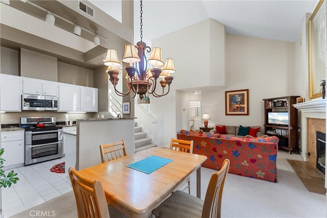 tiled dining space featuring a high ceiling, an inviting chandelier, and a tiled fireplace