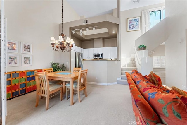 dining room with a notable chandelier, light carpet, and high vaulted ceiling