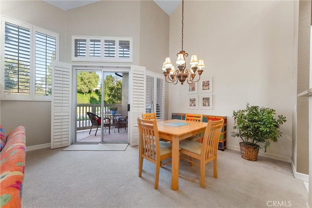 dining space featuring light carpet, an inviting chandelier, and high vaulted ceiling