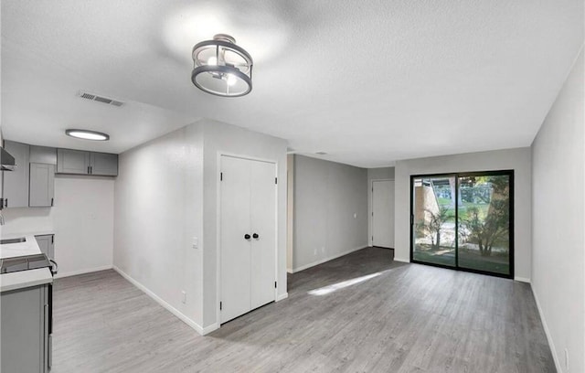 interior space featuring stainless steel stove, light wood-type flooring, tile counters, and gray cabinetry