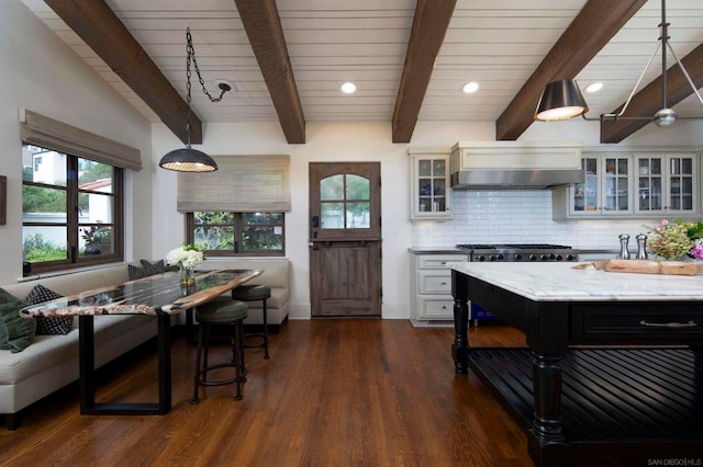 kitchen featuring dark wood-type flooring, hanging light fixtures, sink, white cabinets, and light stone counters