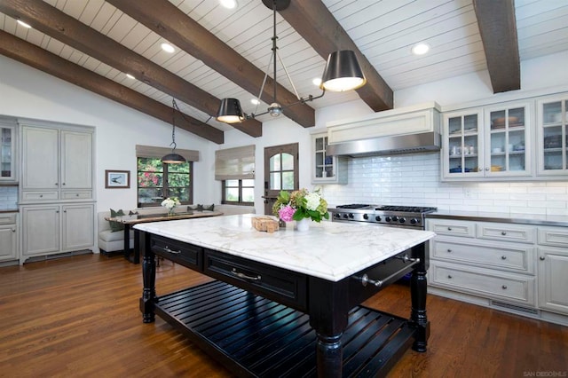 kitchen with a breakfast bar, a center island, vaulted ceiling with beams, and pendant lighting