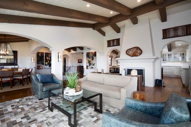 living room with a large fireplace, an inviting chandelier, wooden ceiling, light wood-type flooring, and lofted ceiling with beams