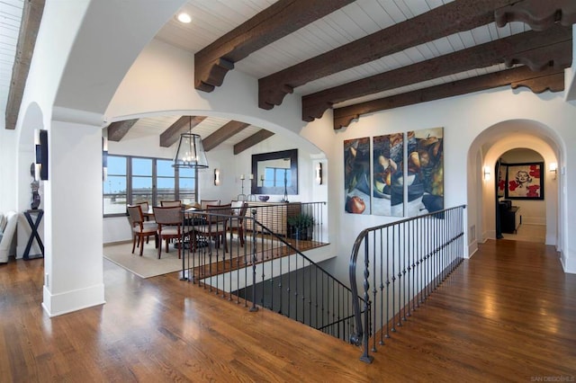 staircase with a notable chandelier, lofted ceiling with beams, wooden ceiling, and wood-type flooring