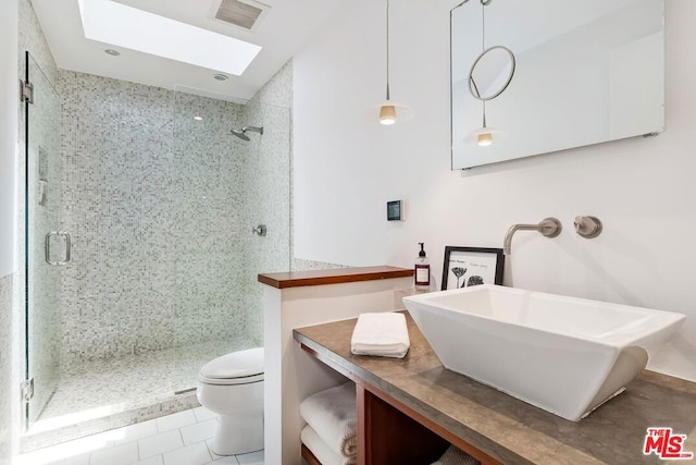 bathroom featuring a skylight, a shower with door, tile patterned floors, vanity, and toilet