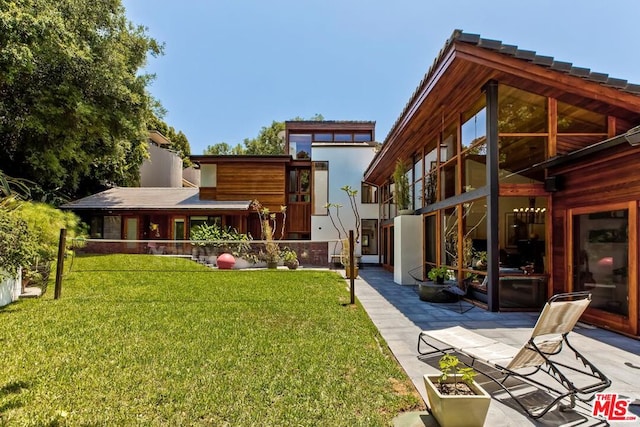 rear view of property featuring a lawn and a patio