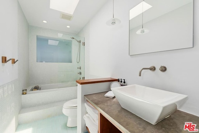 bathroom featuring a tile shower, tile patterned flooring, vanity, and toilet