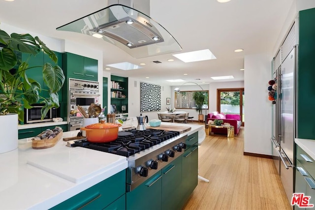 kitchen with light wood-type flooring, a skylight, appliances with stainless steel finishes, and island range hood