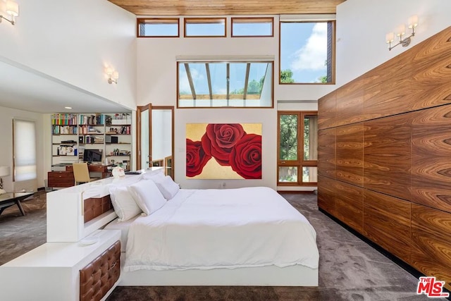 carpeted bedroom featuring a high ceiling and multiple windows