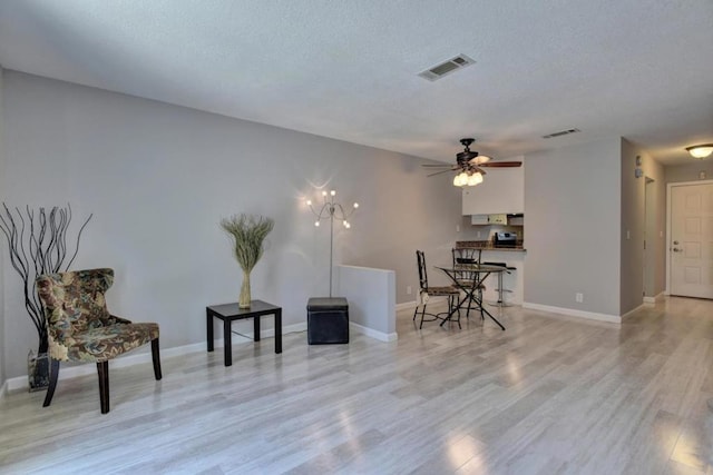 living area featuring a textured ceiling, ceiling fan, and light hardwood / wood-style floors