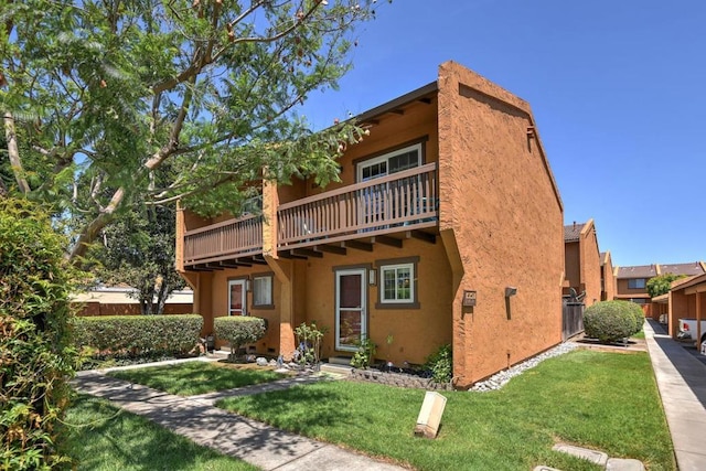 rear view of property featuring a balcony and a yard