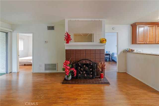 living room featuring a tiled fireplace and light hardwood / wood-style flooring