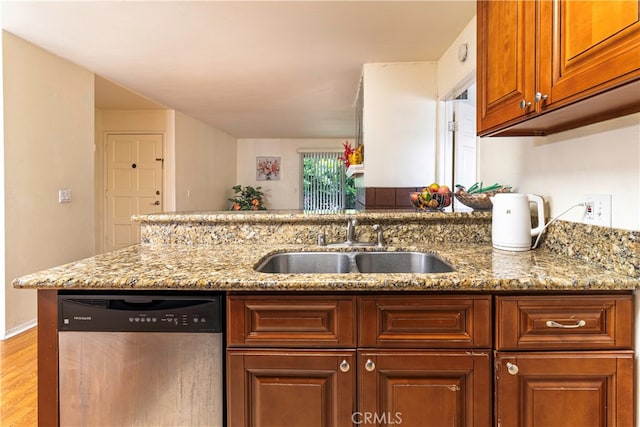 kitchen featuring light stone countertops, light hardwood / wood-style flooring, sink, and stainless steel dishwasher