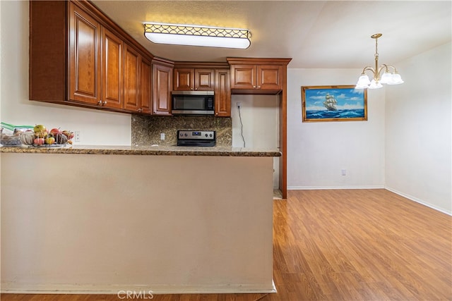 kitchen with light hardwood / wood-style floors, an inviting chandelier, light stone counters, backsplash, and appliances with stainless steel finishes