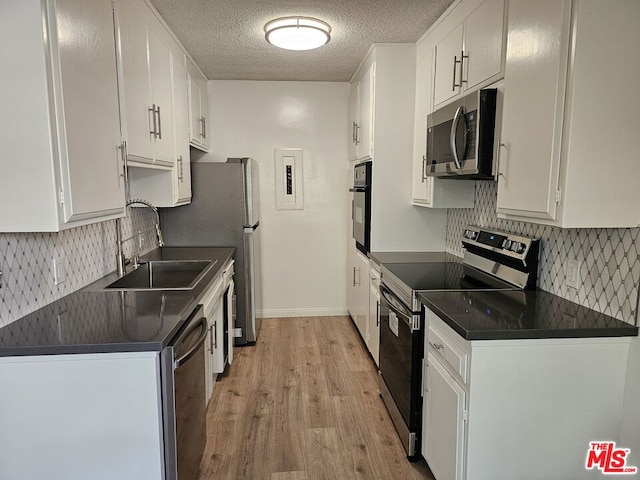 kitchen featuring stainless steel appliances, white cabinetry, light hardwood / wood-style floors, and sink