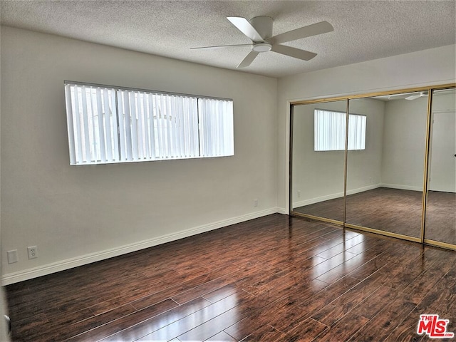 unfurnished bedroom with ceiling fan, a textured ceiling, a closet, and dark wood-type flooring