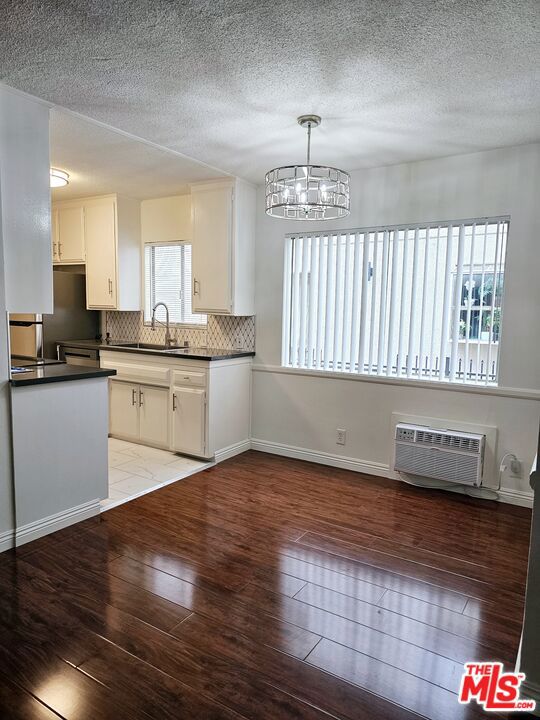 kitchen with a wealth of natural light, hanging light fixtures, light hardwood / wood-style floors, and white cabinetry