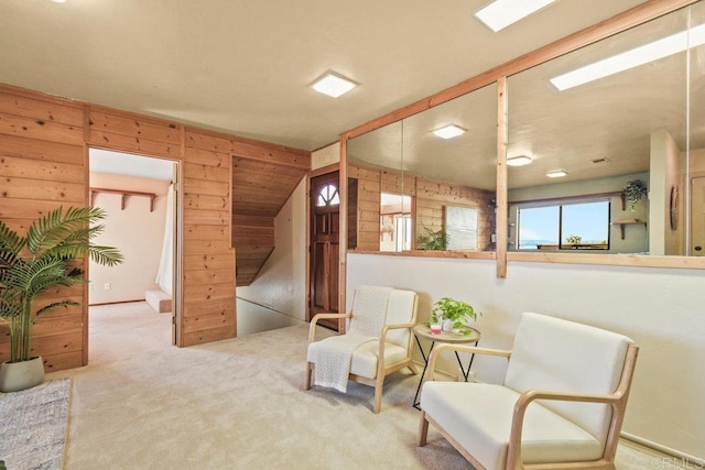 living area featuring wood walls and light colored carpet