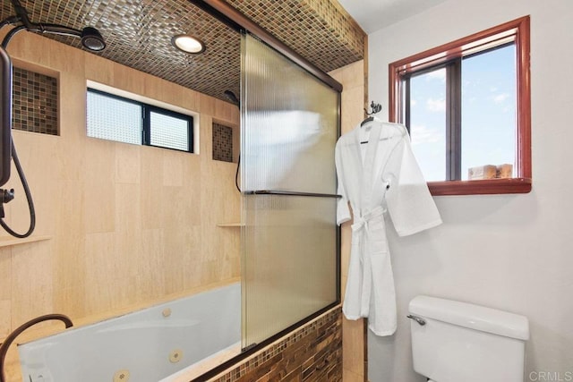 bathroom featuring a wealth of natural light, shower / bath combination with glass door, and toilet