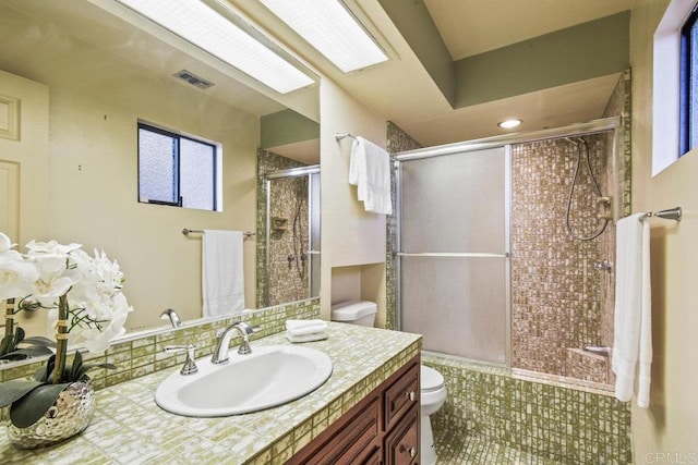 bathroom with decorative backsplash, walk in shower, vanity, and toilet