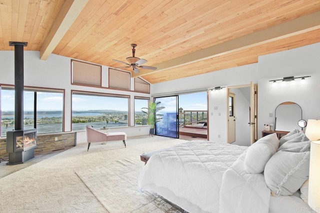 bedroom featuring a wood stove, a water view, ceiling fan, and multiple windows