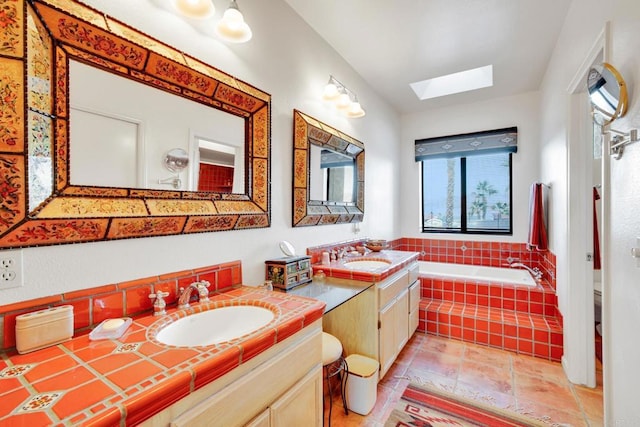 bathroom with tiled bath, vanity, tile patterned flooring, and a skylight