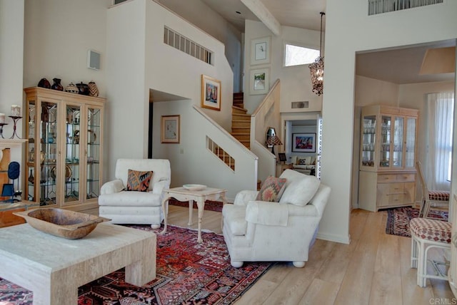 living room featuring light wood-type flooring, a high ceiling, and a notable chandelier